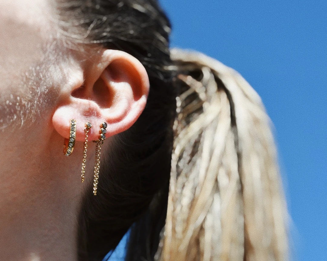 Woman wearing Anne Chain Sparkle Drop Studs layered with other earrings