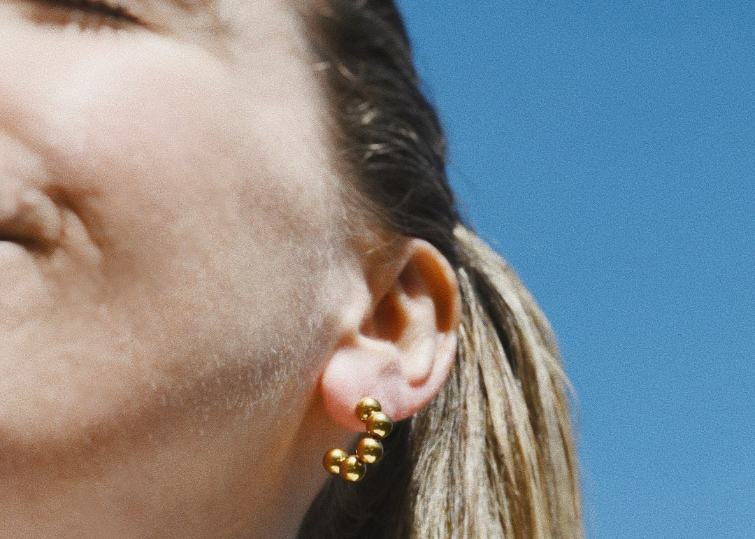 Woman wears the waterproof Amanda small circular gold hoop earring plated