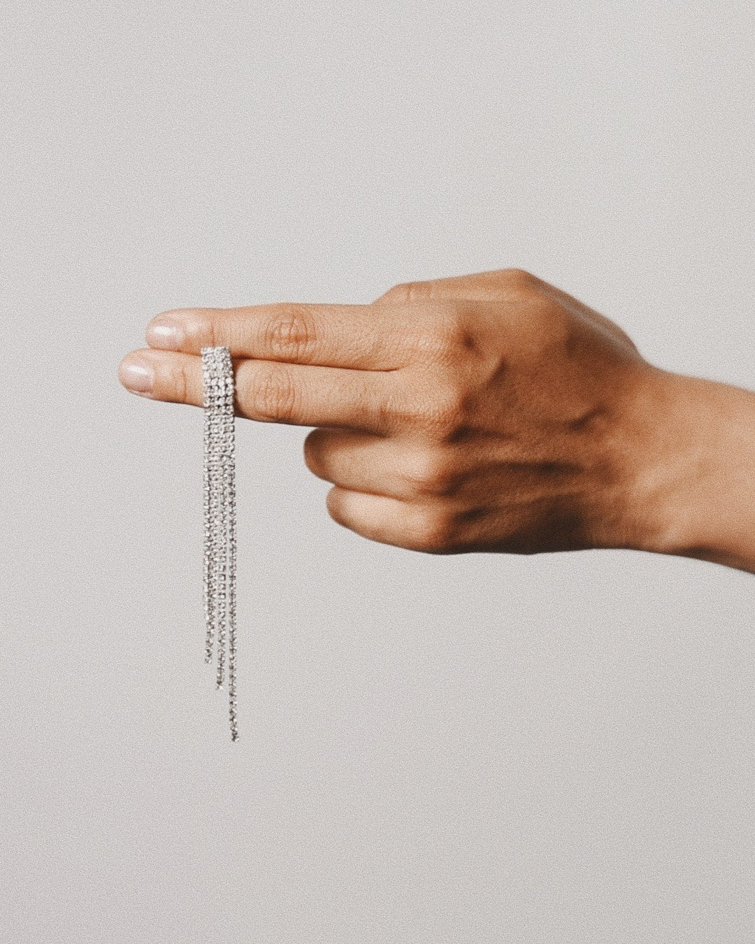 Icy-diamond-drop-silver earrings between fingers