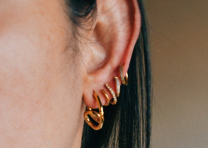 Woman wearing Loop Hoop Earrings and other earrings layered.