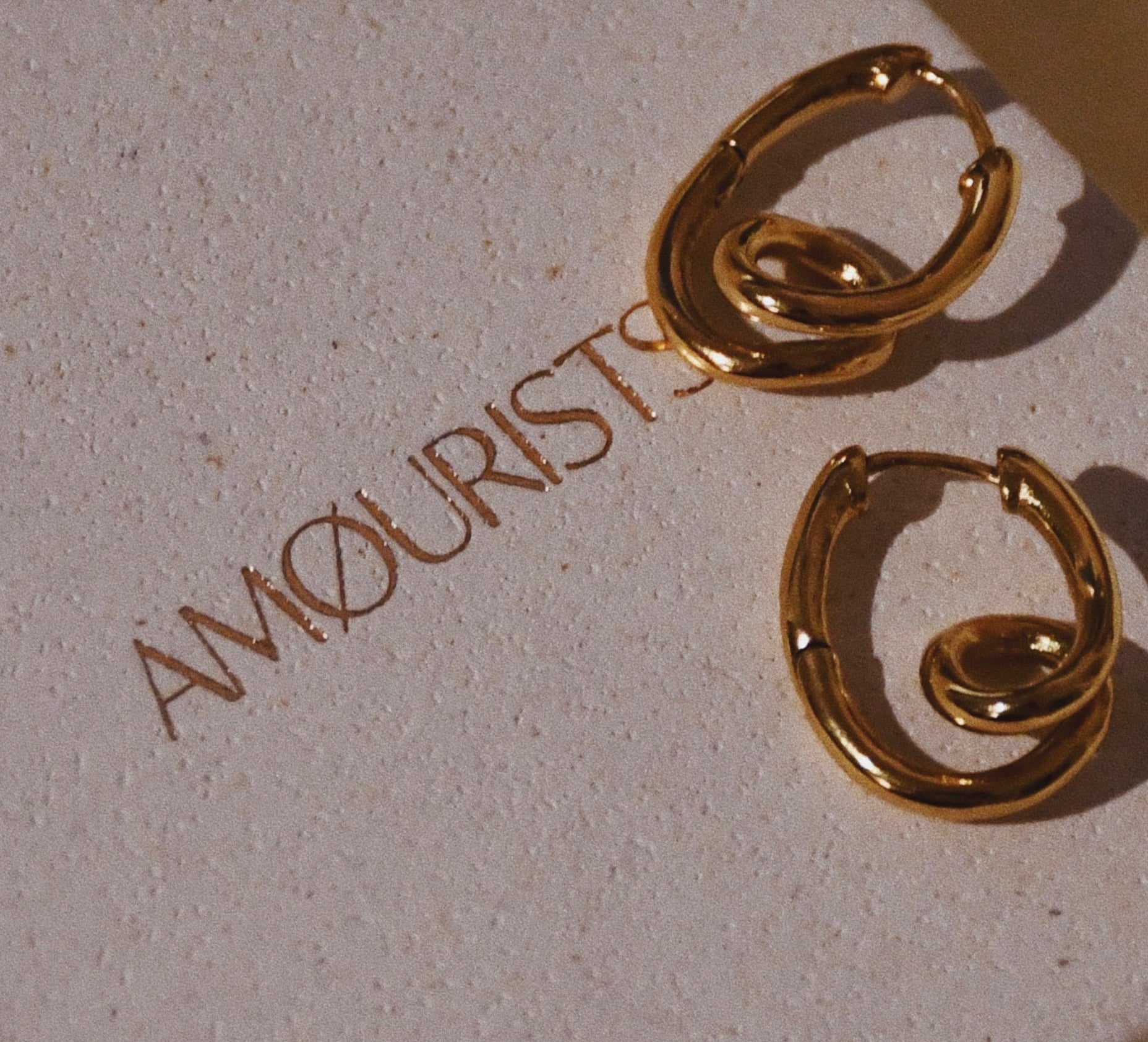 Loop Hoop gold plated earrings on top of the eco Amourists packaging