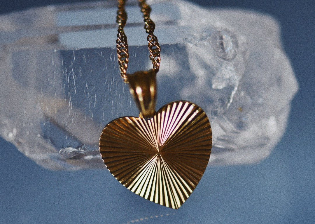 Artistic image of gold-pendant-heart-necklace placed on crystal