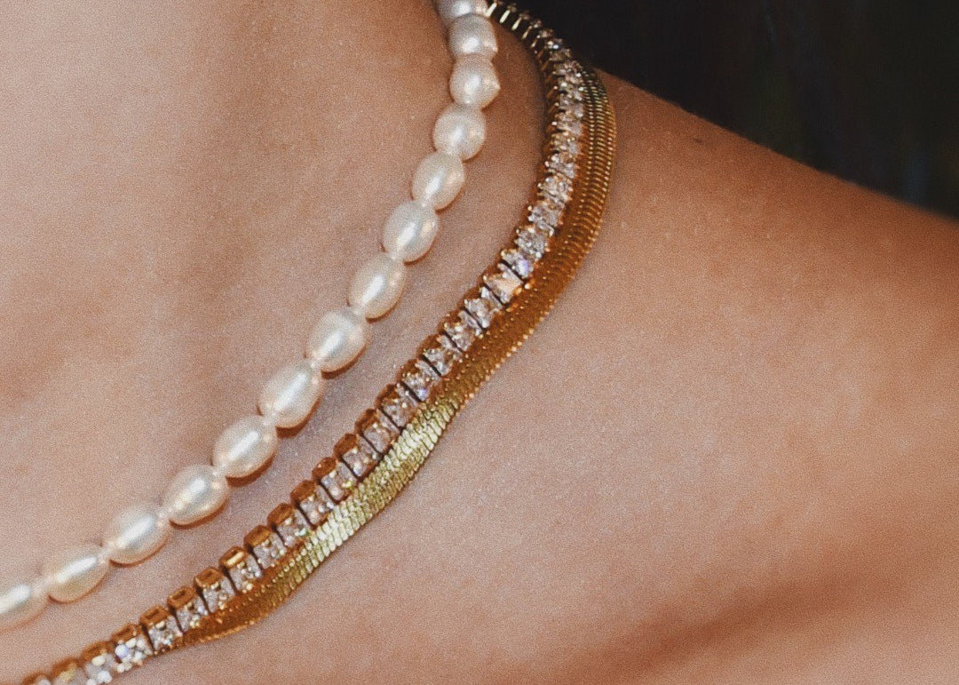 Close-up of a woman wearing 3 necklaces + Aqua – A natural freshwater pearls beaded necklace, snake necklace and diamond gold necklace