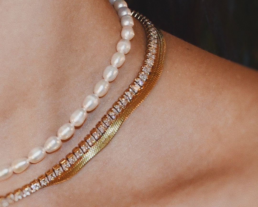 Close-up of a woman wearing 3 necklaces + Aqua – A natural freshwater pearls beaded necklace, snake necklace and diamond gold necklace